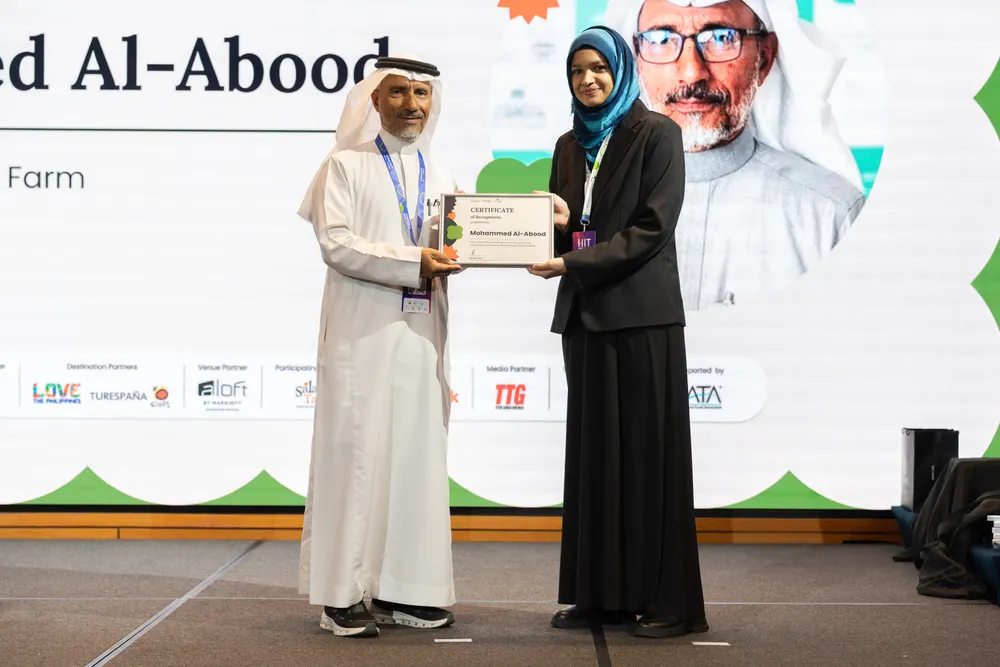 Aayesha Fazal presenting Mohammed Al-Abood with his HalalTrip People Awards certificate of recognition at HITGS.