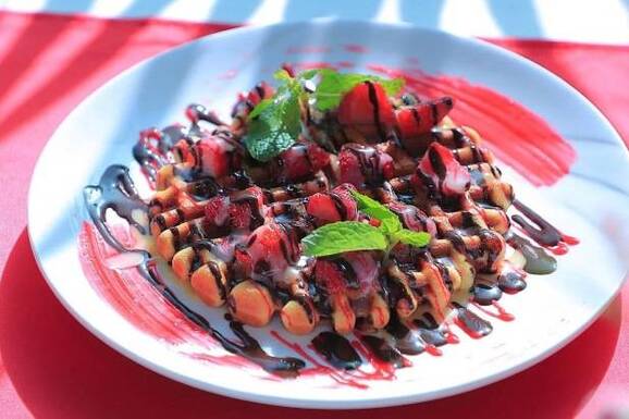 belgian waffle topped with strawberry and chocolate